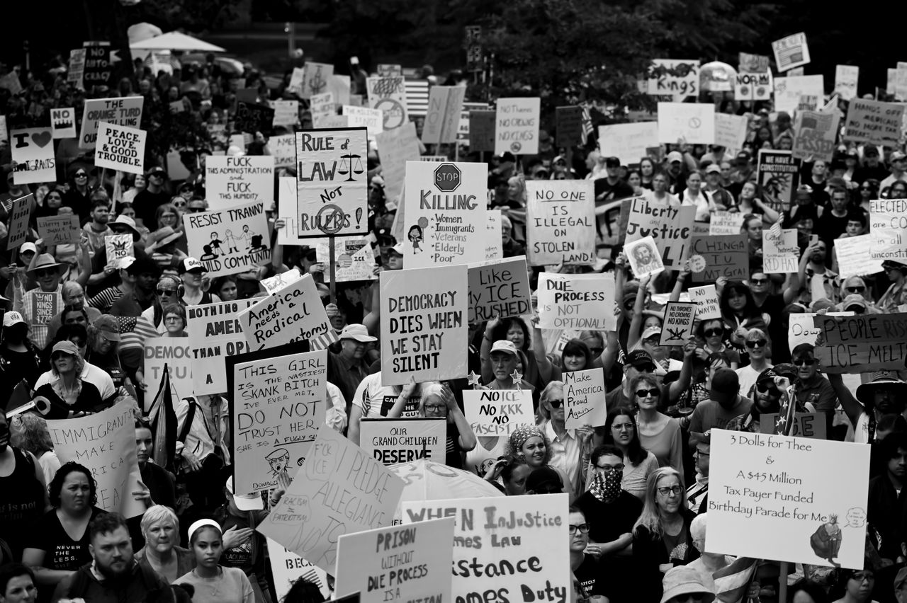 Black and white photo of a large crowd at a political protest holding various signs and slogans.
